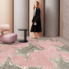 a woman standing in front of a pink rug with leopard print on it and a chair