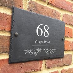 a black slate house number sign mounted to a brick wall