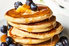 a stack of pancakes with syrup and blueberries