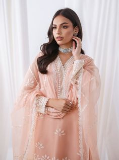 Defining our mesmerizing peach ensemble, which carries you to another dimension of ethereal beauty. Your look effortlessly refines everywhere you go, owing the exquisite cut work on the front of the apparel, which is meticulously crafted with threads, sequence jaal and pattern to add a touch of glamour and refinement. The coordinated pants also feature matching handwork, and the net dupatta is adorned with white embroidery that perfectly contrasts with your apparel. Embrace the romance of summer Zainab Chottani, Sana Safinaz, Another Dimension, Net Dupatta, Ethereal Beauty, White Embroidery, Cut Work, The Net, Chiffon