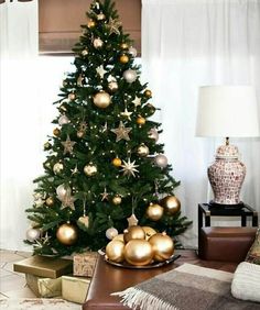 a christmas tree with gold and silver ornaments in a living room decorated for the holidays