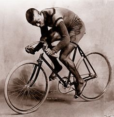 a man riding on the back of a bike while holding onto his hand and looking down