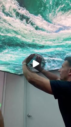 a man is painting a large wave on the wall