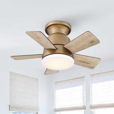 a ceiling fan in a room with two windows