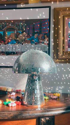 a disco ball lamp sitting on top of a wooden table next to a painting and framed pictures