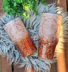 two red glitter tumblers sitting on top of a fur rug