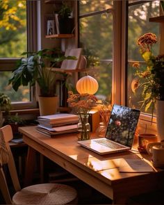 an open laptop computer sitting on top of a wooden desk in front of a window