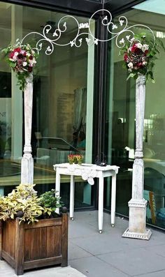 two tall white pillars with flowers on them in front of a glass storefront window