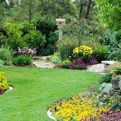 a garden with lots of flowers and rocks in the center, surrounded by green grass