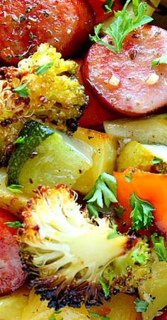 a plate full of vegetables and sausages with seasoning on them, including broccoli