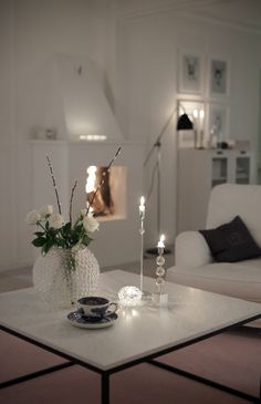 a living room with white furniture and flowers on the coffee table in front of it