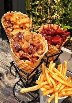 three cones of food sitting on top of a table next to french fries and ketchup