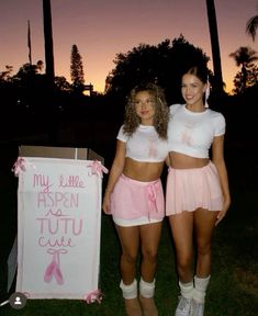 two young women standing next to each other in front of a sign