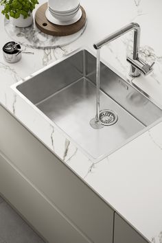 a stainless steel kitchen sink with faucet and soap dispenser next to it