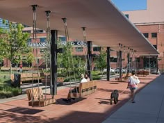 two people and a dog are walking down the sidewalk in front of an outdoor seating area