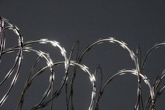 barbed wire is shown against a dark gray background with light coming from the top right corner