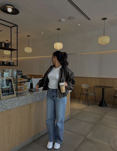 a woman standing in front of a counter holding a cup