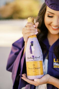 a woman in graduation gown holding a bottle of wine