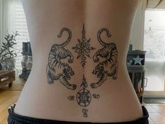 a woman's lower back with two tigers and compass tattoos on her side,