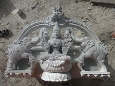 an ornate white statue on the side of a building with two elephants and a vase