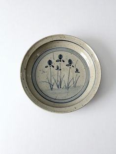 a white and blue plate with flowers on the inside is sitting on a table next to a wall