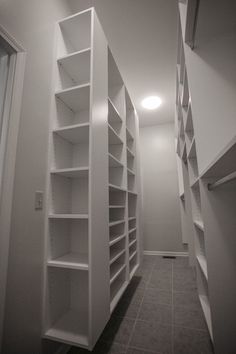 an empty walk in closet with white shelving