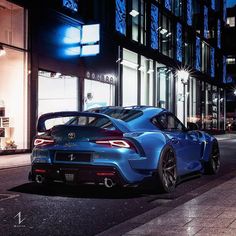 a blue sports car is parked on the side of the road in front of a building