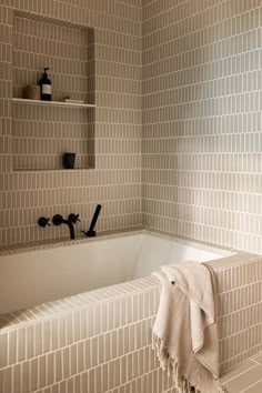 a bath tub sitting under a window next to a shelf