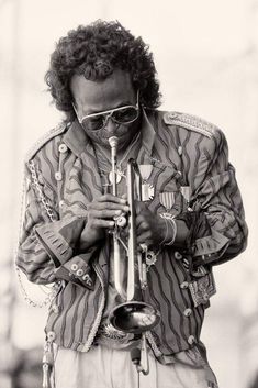 a man wearing sunglasses and holding a trumpet