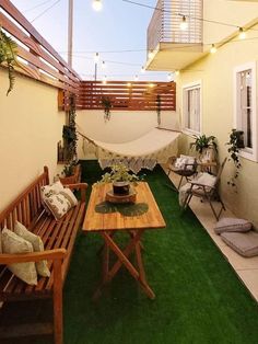 an outdoor patio with hammock, table and chairs on the grass covered ground