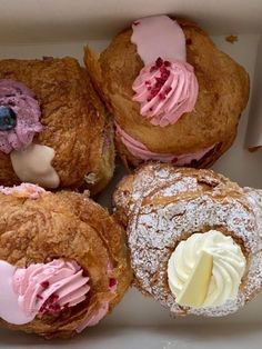 four pastries in a box with icing and powdered sugar