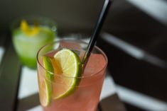 a pink drink with lime and a black straw