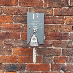 a metal bell mounted to the side of a brick wall with a sign reading station view road