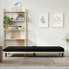 a living room with a couch, bookshelf and pictures on the wall above it