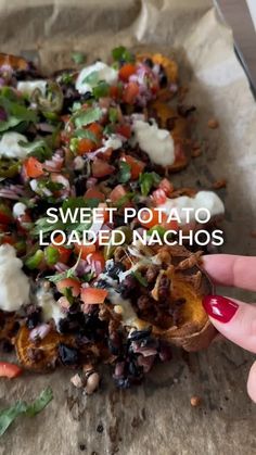 a person holding up a piece of food with the words sweet potato loaded nachos on it