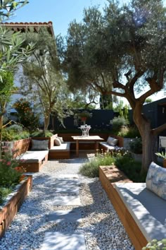 an outdoor seating area with benches and trees in the back ground, surrounded by gravel