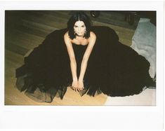 a woman in a black dress sitting on the floor