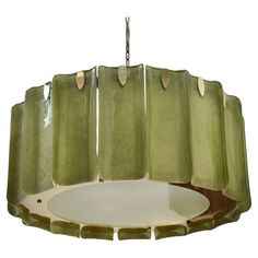 a green chandelier hanging from a ceiling fixture with four lights on each side