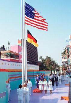 people are standing around in front of a flag pole and building with an american flag on it