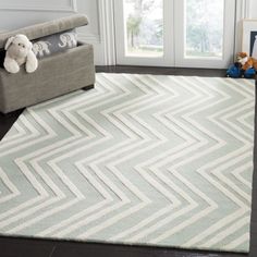 a white and gray area rug with chevron design on the floor in front of a window