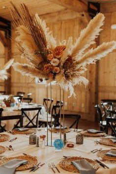 the table is set with place settings and tall centerpieces, which are adorned with dried flowers