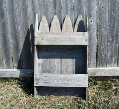 an old wooden box sitting in the grass next to a fence and wood slats