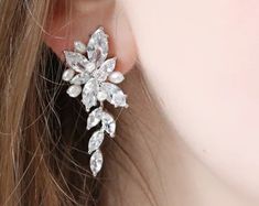 a close up of a woman's ear wearing a pair of earrings with crystals