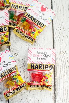 four bags of gummy bears sitting on top of a white wooden table next to each other