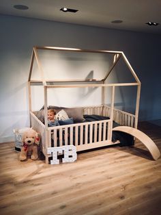 a little boy laying in his bed next to a teddy bear and a wooden sign