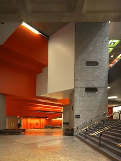 an empty lobby with stairs and orange walls