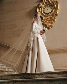 a woman in a wedding dress standing next to a clock