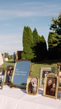 a table topped with pictures and frames on top of a white cloth covered tablecloth