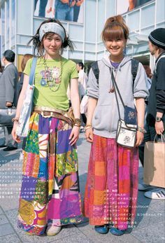 two young women standing next to each other in front of a building with lots of people