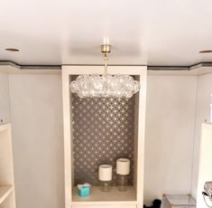 a room with a shelf, shelves and a chandelier hanging from the ceiling